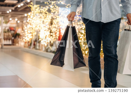 Man is standing in the mall and holding packages Man is standing in the mall and holding packages 139275190