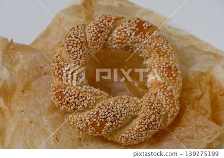Freshly baked sesame bread ring rests on parchment paper, showcasing its golden brown crust and delicate texture, ready to be enjoyed Freshly baked sesame bread ring rests on parchment paper, showcasing its golden brown crust and delicate texture, ready to be enjoyed 139275199