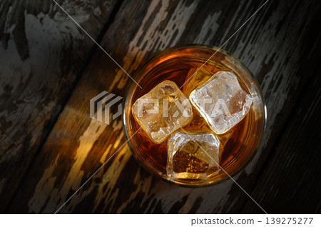 Sip on smooth flavors as ice melts in a refreshing glass of amber spirit at sunset 139275277