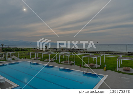 Calm evening by the seaside pool under a cloudy sky with distant mountains 139275278