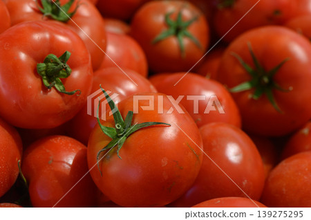 Fresh red tomatoes piled high in a vibrant market stall, inviting shoppers to indulge in nature's bounty of flavors Fresh red tomatoes piled high in a vibrant market stall, inviting shoppers to indulge in nature's bounty of flavors 139275295