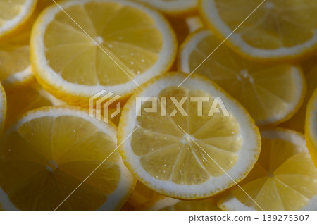 Bright yellow lemon slices shimmering under soft sunlight, creating a vibrant display in a kitchen setting Bright yellow lemon slices shimmering under soft sunlight, creating a vibrant display in a kitchen setting 139275307