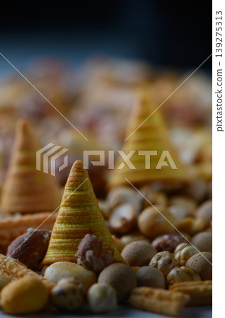Deliciously crafted conical snacks surrounded by a medley of nuts and treats on a rustic surface Deliciously crafted conical snacks surrounded by a medley of nuts and treats on a rustic surface 139275313