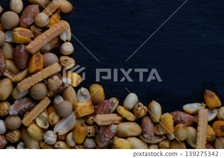 Variety of colorful snacks arranged artistically on a dark surface, showcasing texture and natural hues in an alluring composition 139275342