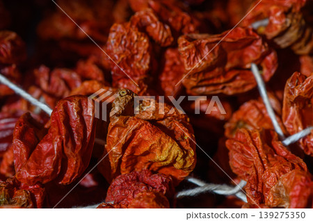 Dried red chili peppers hanging in a traditional marketplace showcasing vibrant colors and rich textures Dried red chili peppers hanging in a traditional marketplace showcasing vibrant colors and rich textures 139275350