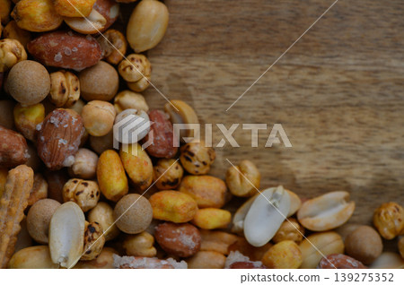 Colorful mix of roasted nuts and snacks beautifully arranged on natural wood background Colorful mix of roasted nuts and snacks beautifully arranged on natural wood background 139275352