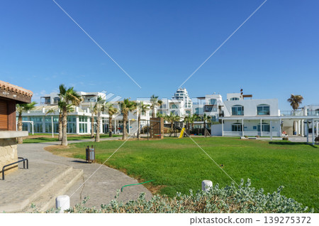 A sunny afternoon at a coastal resort featuring modern architecture and lush green spaces. 139275372
