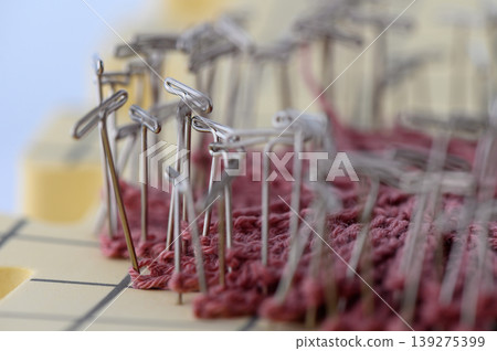Pinning Wet Knitted Fabric for Blocking on White Background Pinning Wet Knitted Fabric for Blocking on White Background 139275399