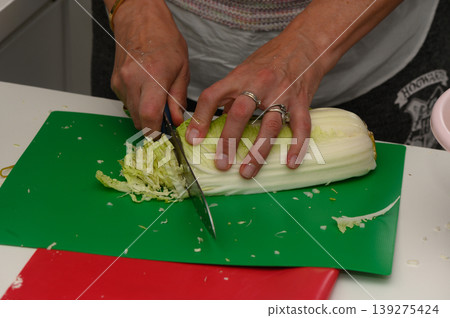 Chopping fresh cabbage for delicious spring rolls in a bright kitchen during a lively cooking session 139275424