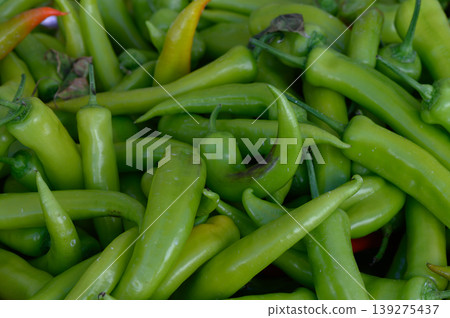 Lush green peppers piled high at a bustling outdoor market in the afternoon sun Lush green peppers piled high at a bustling outdoor market in the afternoon sun 139275437