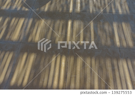 Sunlight casts intricate patterns on a tiled floor, creating a mesmerizing display of shadows. Sunlight casts intricate patterns on a tiled floor, creating a mesmerizing display of shadows. 139275553