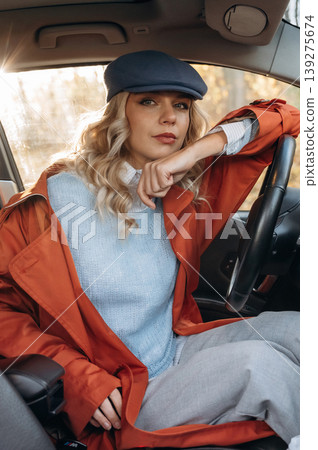 On the steering wheel, resting. Happy blonde woman is sitting her electric car On the steering wheel, resting. Happy blonde woman is sitting her electric car 139275674
