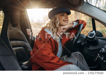 Comfortable interior, relax. Happy blonde woman is sitting her electric car Comfortable interior, relax. Happy blonde woman is sitting her electric car 139275680