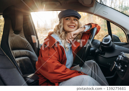 Comfortable interior, relax. Happy blonde woman is sitting her electric car Comfortable interior, relax. Happy blonde woman is sitting her electric car 139275681