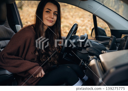 Looking at the camera, feeling good. Beautiful woman is sitting in her electric car 139275775