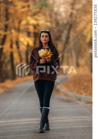 A woman is standing on the asphalt road outdoors at autumn season A woman is standing on the asphalt road outdoors at autumn season 139275838