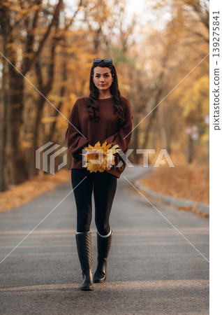 A woman is standing on the asphalt road outdoors at autumn season A woman is standing on the asphalt road outdoors at autumn season 139275841