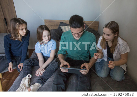 Group of children watching a video together on a tablet in a living room during the afternoon Group of children watching a video together on a tablet in a living room during the afternoon 139276058