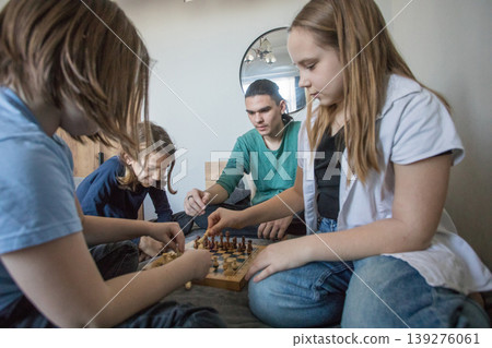 Group of children play chess together in a living room during an afternoon gathering Group of children play chess together in a living room during an afternoon gathering 139276061