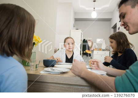 Four people sit together at a table in a dining area, enjoying food and drinks. 139276070