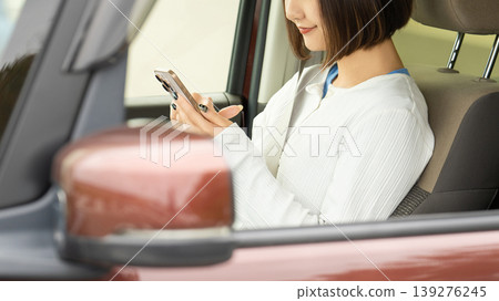 一名女子在車內使用智慧型手機。 139276245