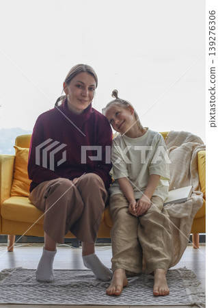 Cute mother and daughter sitting on couch at home Cute mother and daughter sitting on couch at home 139276306