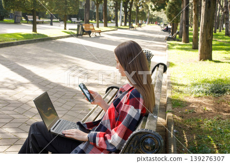 Pretty woman using smartphone while using laptop and working in Pretty woman using smartphone while using laptop and working in 139276307