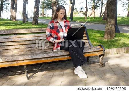 Serious woman using laptop in park outdoors Serious woman using laptop in park outdoors 139276308