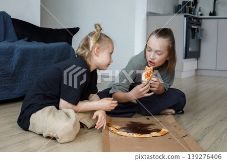 Lovely children eating pizza and having fun wile sitting on floor 139276406