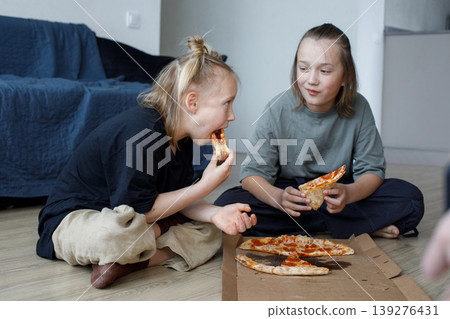 Smiling friends girl and boy eating pizza at home Smiling friends girl and boy eating pizza at home 139276431