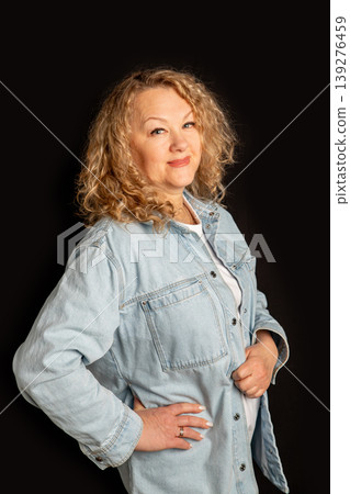Woman designer in denim shirt posing against black background. Middle aged businesswoman showing professional confidence and style. Successful female entrepreneur portrait for lifestyle concept. 139276459