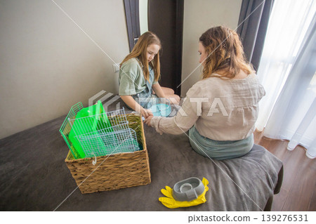 Two people sort pet supplies on a bed in a room with natural light during the day Two people sort pet supplies on a bed in a room with natural light during the day 139276531
