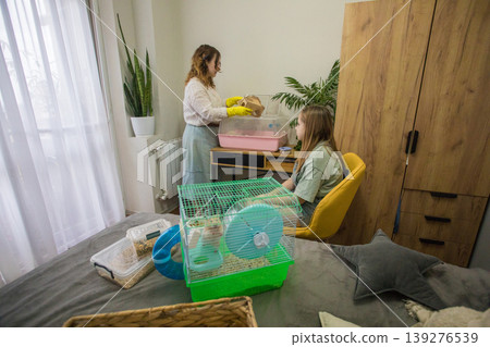 In a bright room, a woman in gloves helps another person with small pets. In a bright room, a woman in gloves helps another person with small pets. 139276539