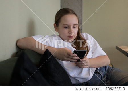Portrait of preteen child holding mobile cell phone. Girl playing games Portrait of preteen child holding mobile cell phone. Girl playing games 139276743