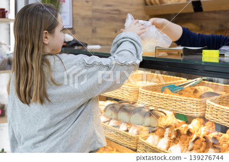 Cute young girl chooses bread. Grocery store shelves. Bakery department. Fresh pastries Cute young girl chooses bread. Grocery store shelves. Bakery department. Fresh pastries 139276744