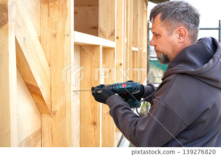 Carpenter man using electric screwdriver to fix wooden beam Carpenter man using electric screwdriver to fix wooden beam 139276820