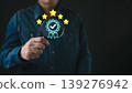 A businessman holding a digital hologram of a quality assurance badge with five stars, symbolizing customer satisfaction, trust, excellence, and business service quality in modern technology. 139276942