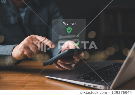 Man making secure online payment using smartphone and laptop with digital interface, concept of mobile banking, fintech, e-commerce transaction, and financial technology security. Man making secure online payment using smartphone and laptop with digital interface, concept of mobile banking, fintech, e-commerce transaction, and financial technology security. 139276944