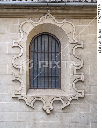 Ornate Arched Stone Window With Decorative Surround and Iron Grille on Historic Facade Ornate Arched Stone Window With Decorative Surround and Iron Grille on Historic Facade 139277189
