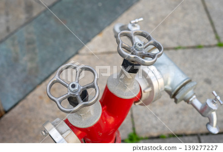 View of two overhead fire hydrant valves in lush red color next to the street View of two overhead fire hydrant valves in lush red color next to the street 139277227