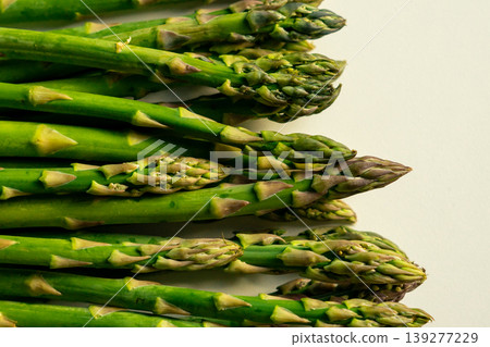 View of green asparagus lying in a row on a white table in sunlight View of green asparagus lying in a row on a white table in sunlight 139277229