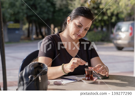 Freelancer Woman Handling Paperwork in Coffee Shop. Freelancer Woman Handling Paperwork in Coffee Shop. 139277290