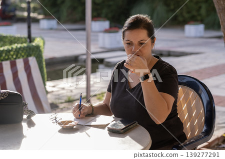 Freelancer Woman Handling Paperwork in Coffee Shop.  139277291