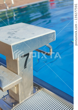 Side view of the starting block of an outdoor swimming pool during the summer Side view of the starting block of an outdoor swimming pool during the summer 139277591