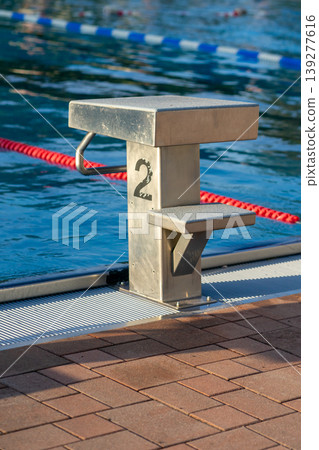 Side view of the starting block of an outdoor swimming pool in the summer season Side view of the starting block of an outdoor swimming pool in the summer season 139277616