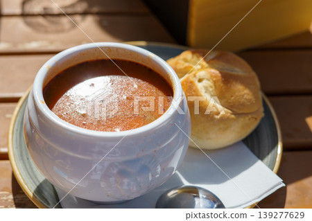 Traditional Hungarian thick goulash soup in a white deep plate served with bread Traditional Hungarian thick goulash soup in a white deep plate served with bread 139277629