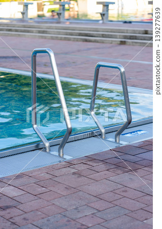 Staircase with handrails in blue swimming pool in outdoor swimming pool 139277639