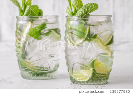 Two fresh mojito cocktails in tiki glasses with lime mint garnish 139277980