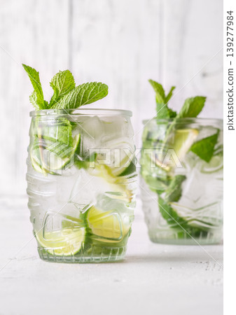 Two fresh mojito cocktails in tiki glasses with lime mint garnish Two fresh mojito cocktails in tiki glasses with lime mint garnish 139277984