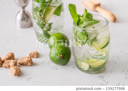 Two fresh mojito cocktails in tiki glasses with lime mint garnish Two fresh mojito cocktails in tiki glasses with lime mint garnish 139277986